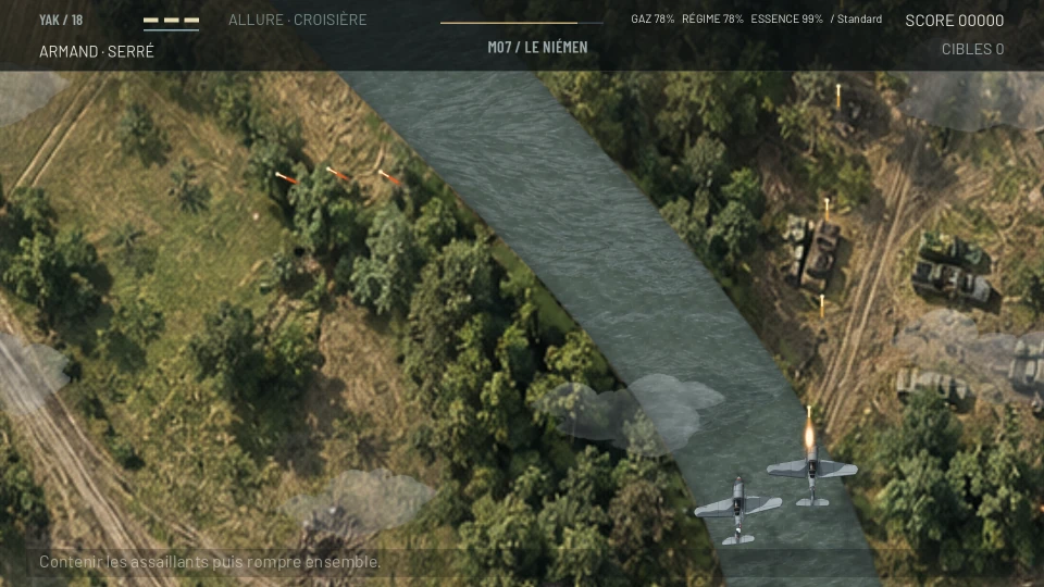 Two grey Yak fighters above a wide river running between wooded banks, one of them firing; military vehicles stand along a track on the right bank and three red tracer rounds cross the upper left; the order line says to hold off the attackers, then break away together